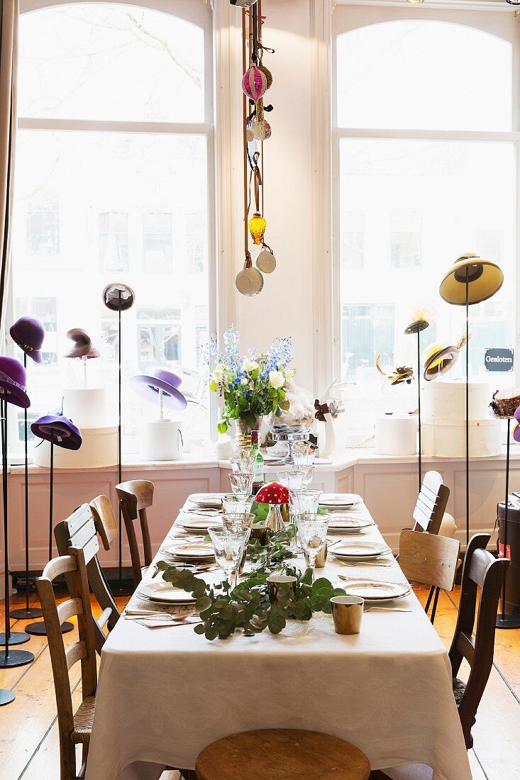 Set table surrounded by various hats on hat stands
