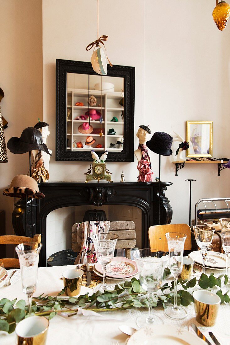 Set table surrounded by hat stands in front of black mantelpiece
