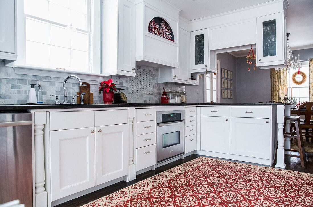 Traditional, red and white patterned rug in modern country-house kitchen with poinsettia in red pot
