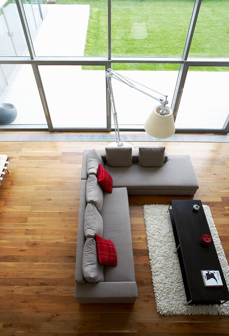 Blick auf eleganten Sitzbereich mit Edelholz-Parkettboden, Fensterfront und Gartenblick
