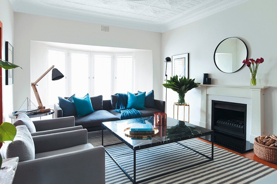Eleganter Couchtisch auf Streifenteppich, Sessel und Sofa in verschiedenen Grautönen in traditionellem Wohnzimmer
