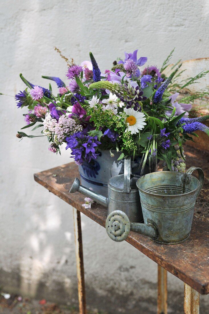 Blue and white summer bouquet and zinc watering can on table