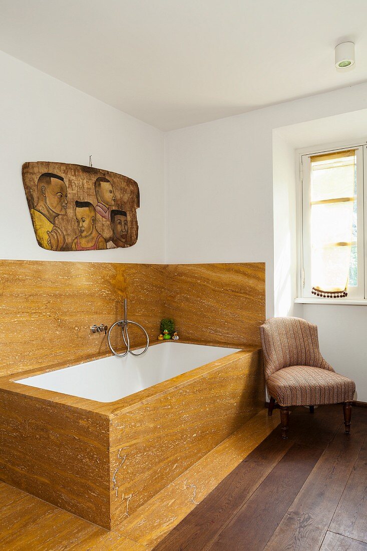 Bathtub clad in ochre stone in elegant country-house bathroom