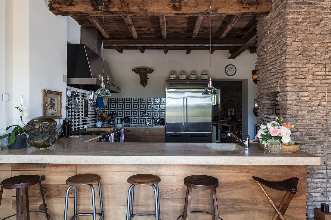 Breakfast bar and rustic wood-beamed ceiling in open-plan country-house kitchen