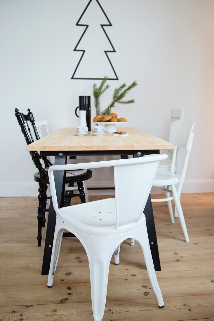 Esstisch mit verschiedenen schwarzen und weißen Stühlen, Weihnachtsbaum-Kontur an der Wand