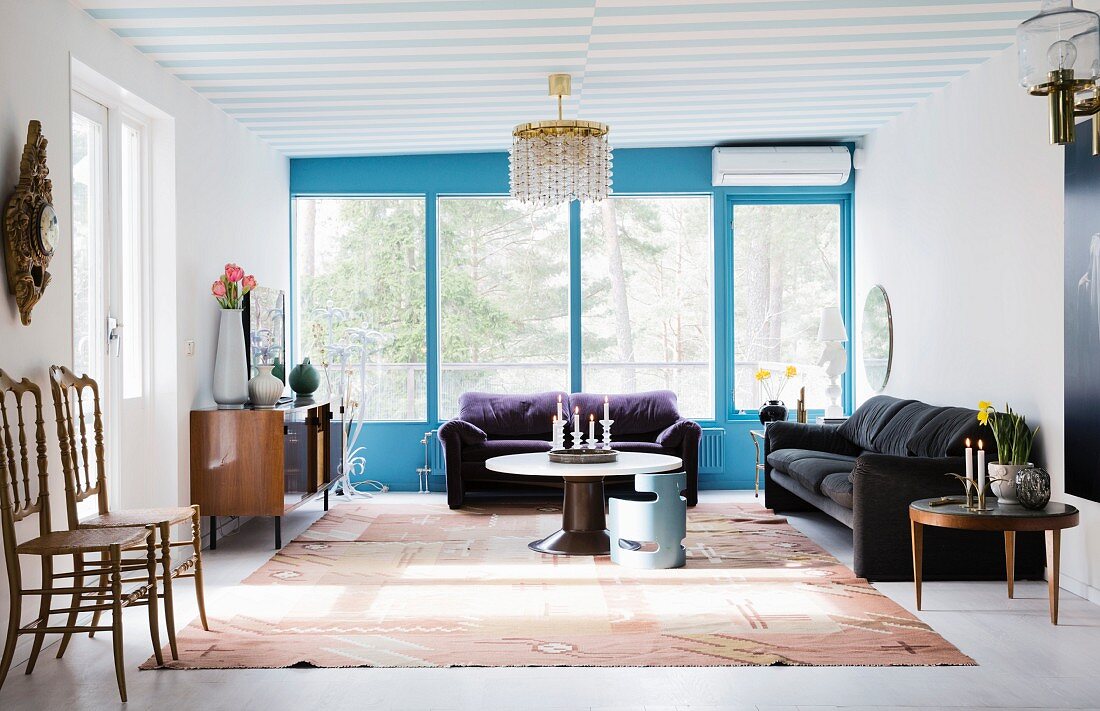 Luftiges Wohnzimmer mit blauen Fensterrahmen und Retromöbeln