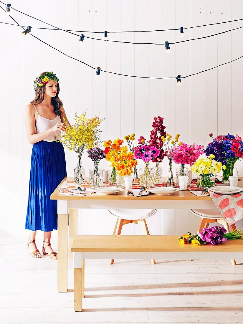 Junge Frau mit Blumenkranz an schlichtem Holztisch mit üppiger Blumendeko