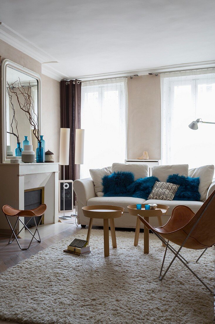 Helles gemütliches Wohnzimmer mit Klassikermöbeln, Kamin und blauen Kissenbezügen