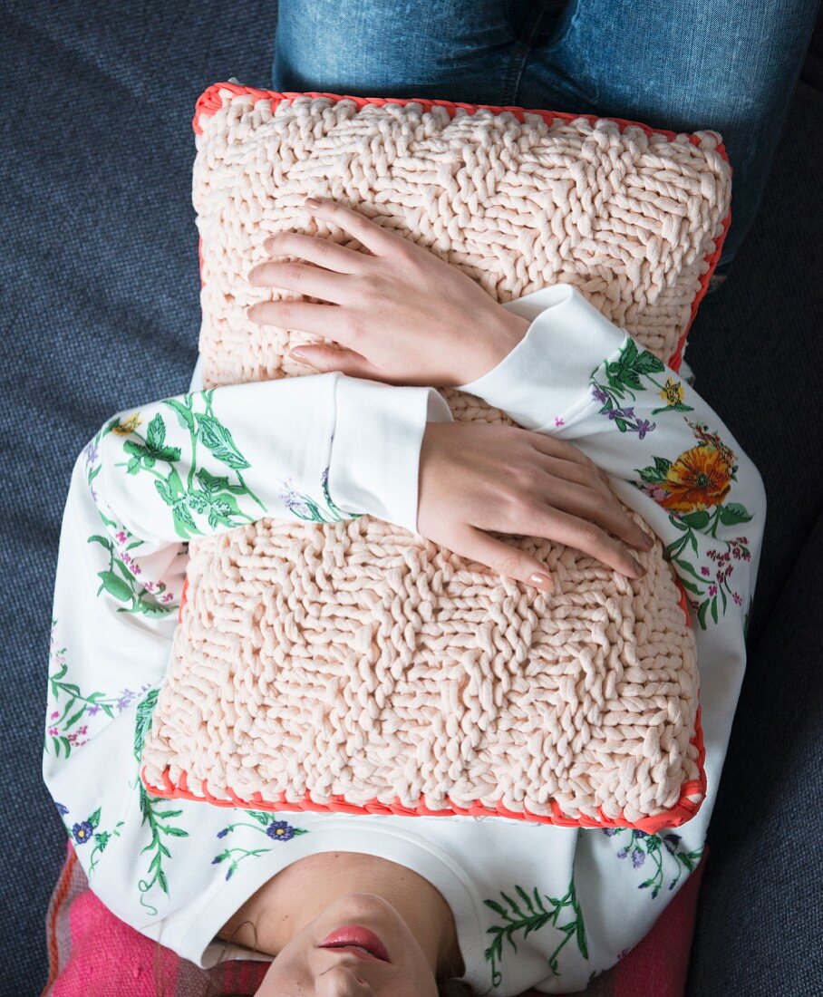 A woman holding a knooked cushion - knitting with a hook