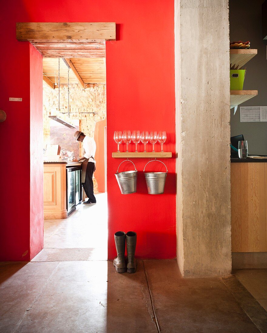 Fire-engine-red wall with view of bar counter through narrow doorway