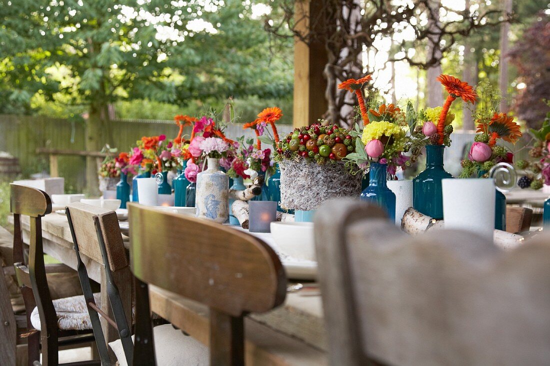 Gedeckter, rustikaler Holztisch mit mit Herbstblumen dekoriert, im Freien