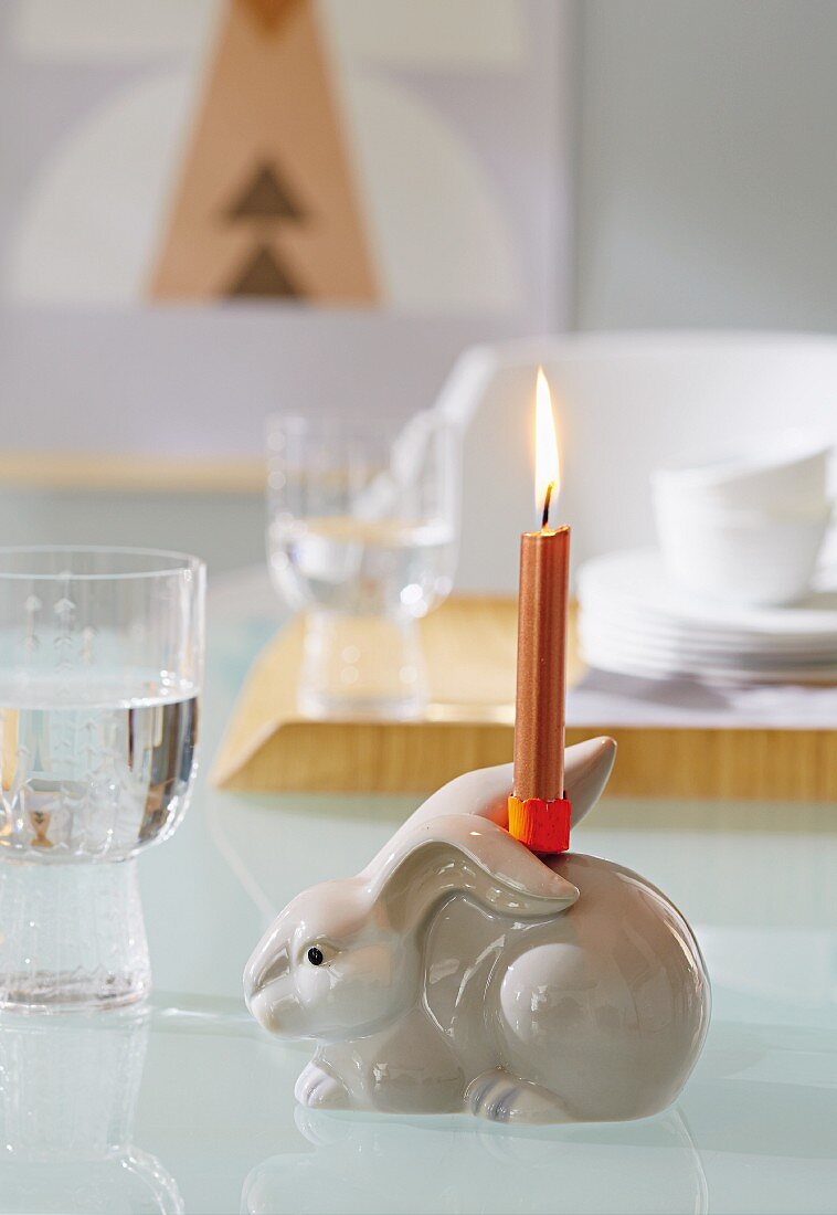 Porzellanhase mit aufgeklebtem Kerzenhalter und brennende Kerze