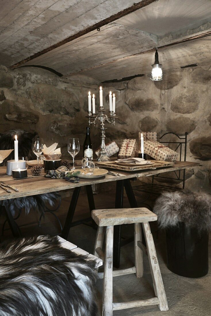 Weihnachten im Weinkeller: gedeckter rustikaler Holztisch mit Wein und Kerzen