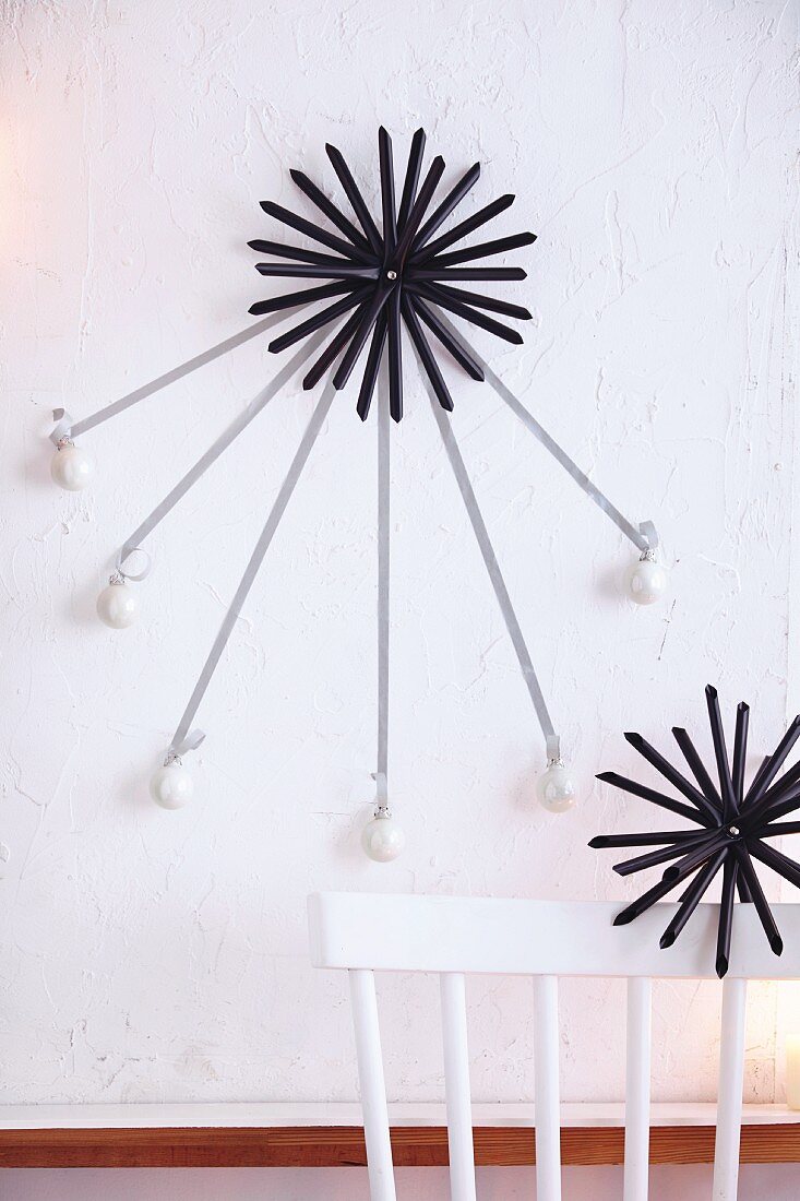 Straw stars hung with mini Christmas baubles as wall decoration