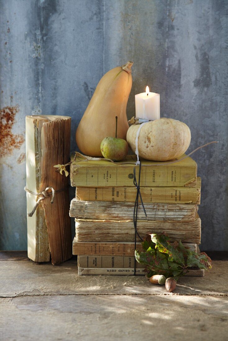 Herbstliches Arrangement aus antiken Büchern, Zierkürbissen & Kerze