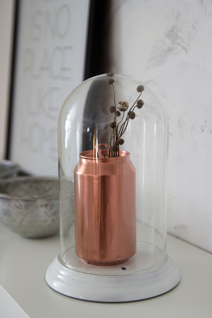 Kupferfarbene Getränkedose als Vase unter Glashaube