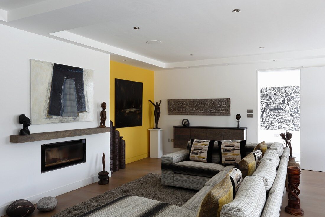 Sofa combination in front of fireplace, yellow wall and artworks