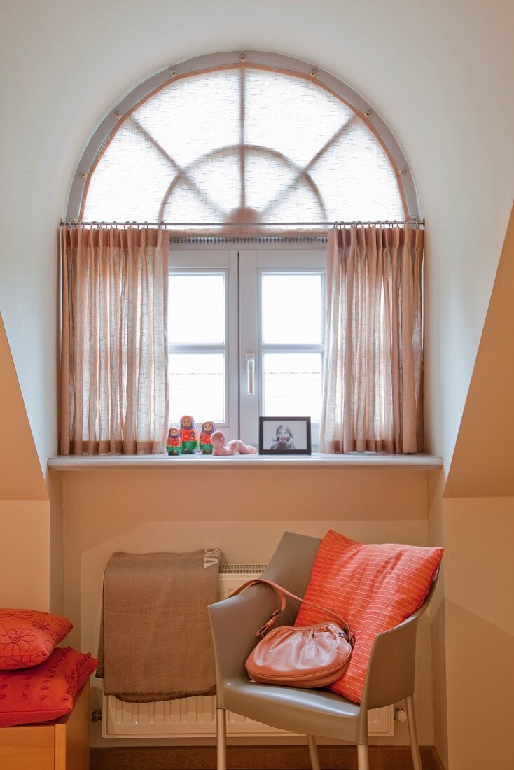 Designerstuhl mit hellbraunem Lederbezug vor apricotfarbener Wand, Fenster mit Oberlicht in Rundgaube