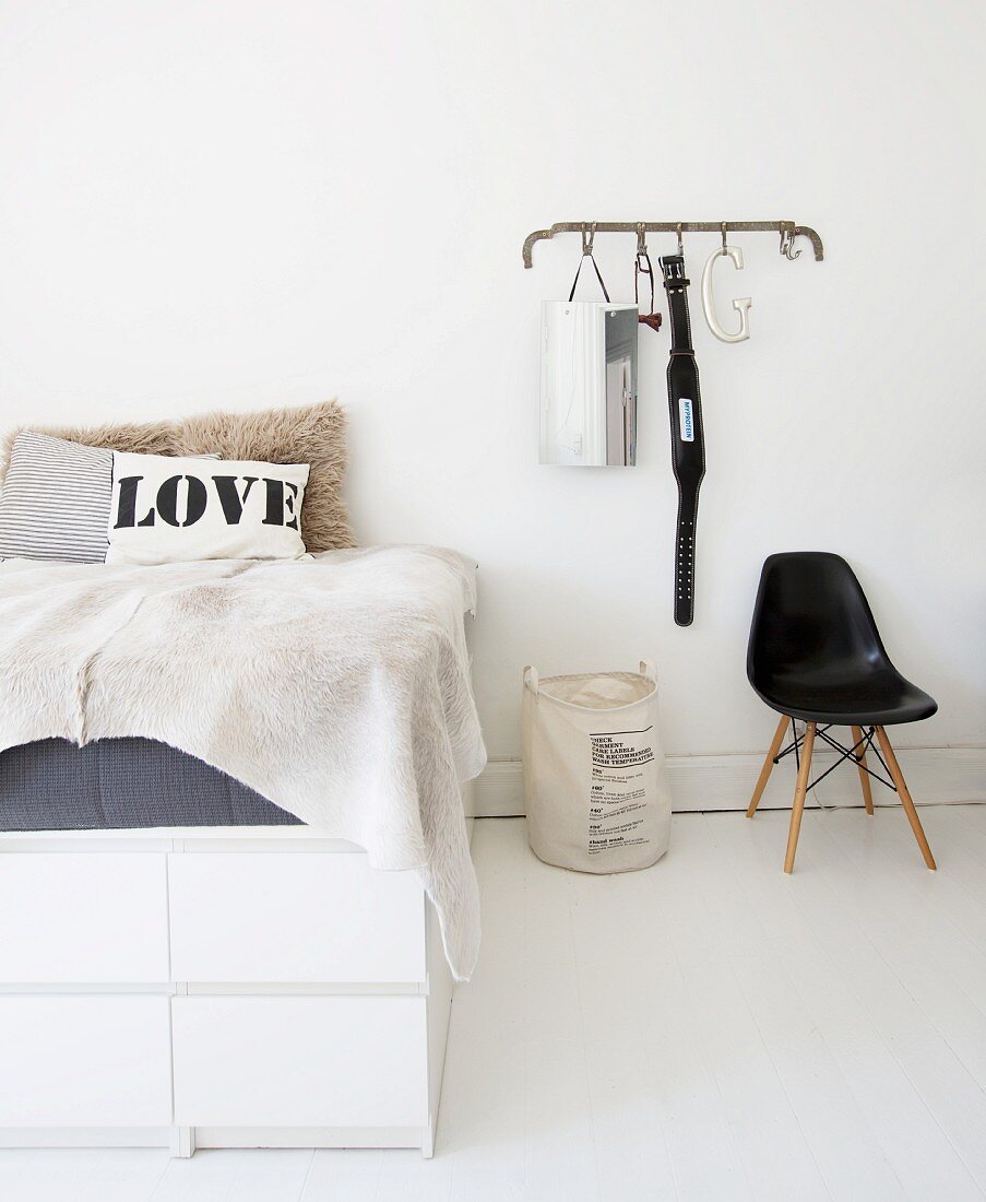Selbstgebautes Bett auf weißen Kommoden neben einer Garderobe