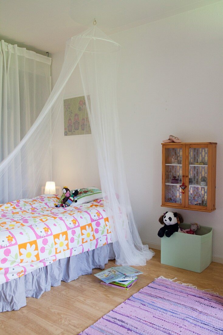 Mosquito net over bed in child's bedroom in pastel shades