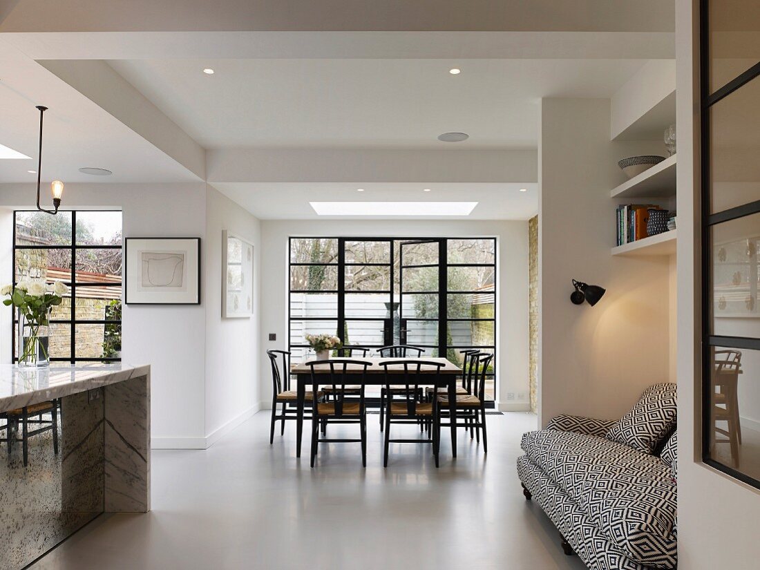 Open-plan interior with white floor, dining area and sofa in niche