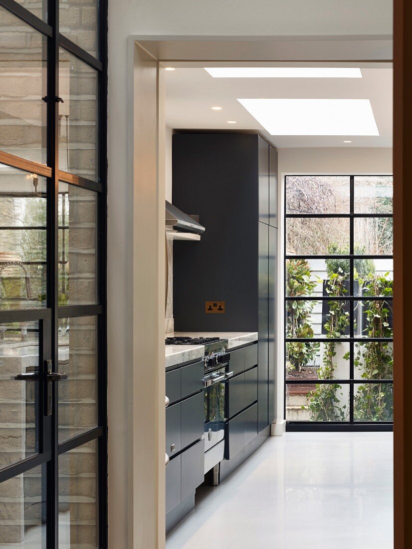 View into kitchen with black fronts and floor-to-ceiling windows
