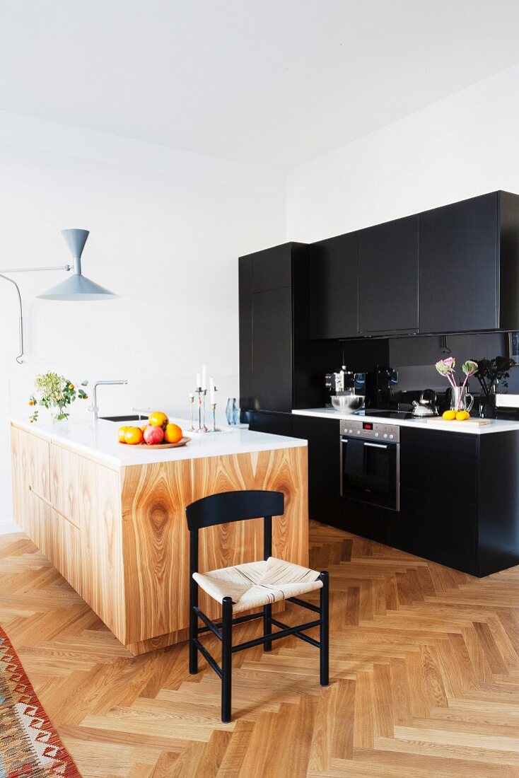 Schwarze Küchenzeile und helle Kücheninsel mit Holzmaserung in renovierter Altbauwohnung