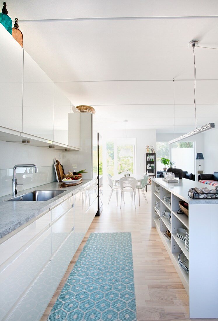 Open-plan kitchen with white glossy fronts and island counter