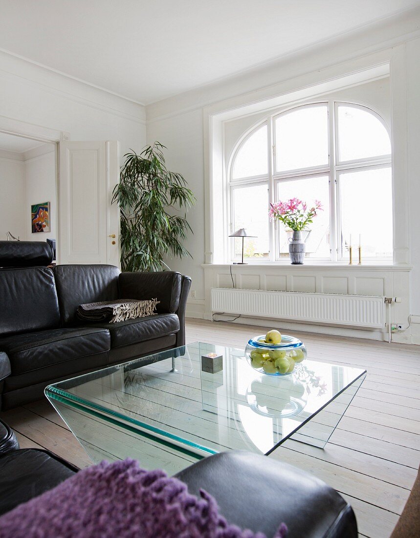 Loungebereich mit Ledercouch und Glastisch in renovierter Altbauwohnung