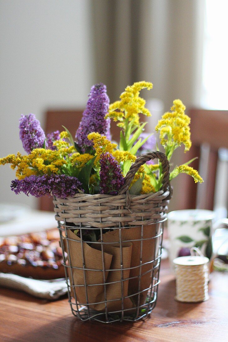 Wire basket of yellow and purple flowers decorating table
