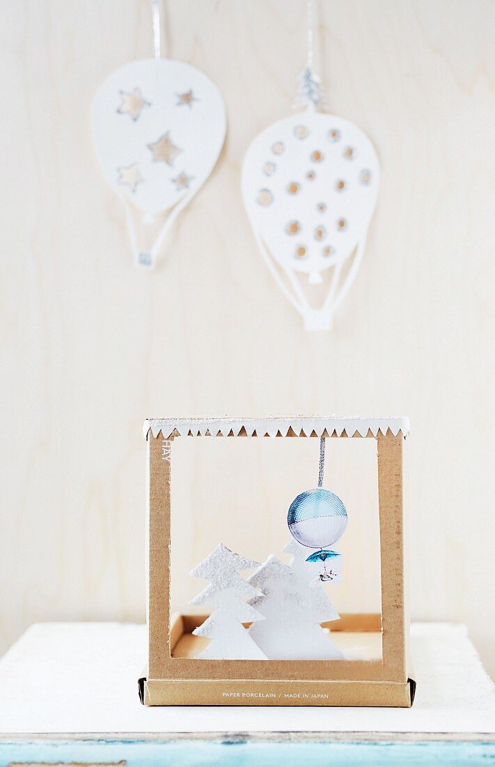 DIY-Weihnachtsdekoration aus Karton, ausgeschnittenen Papier-Tannenbäumchen und Ballon-Motiven