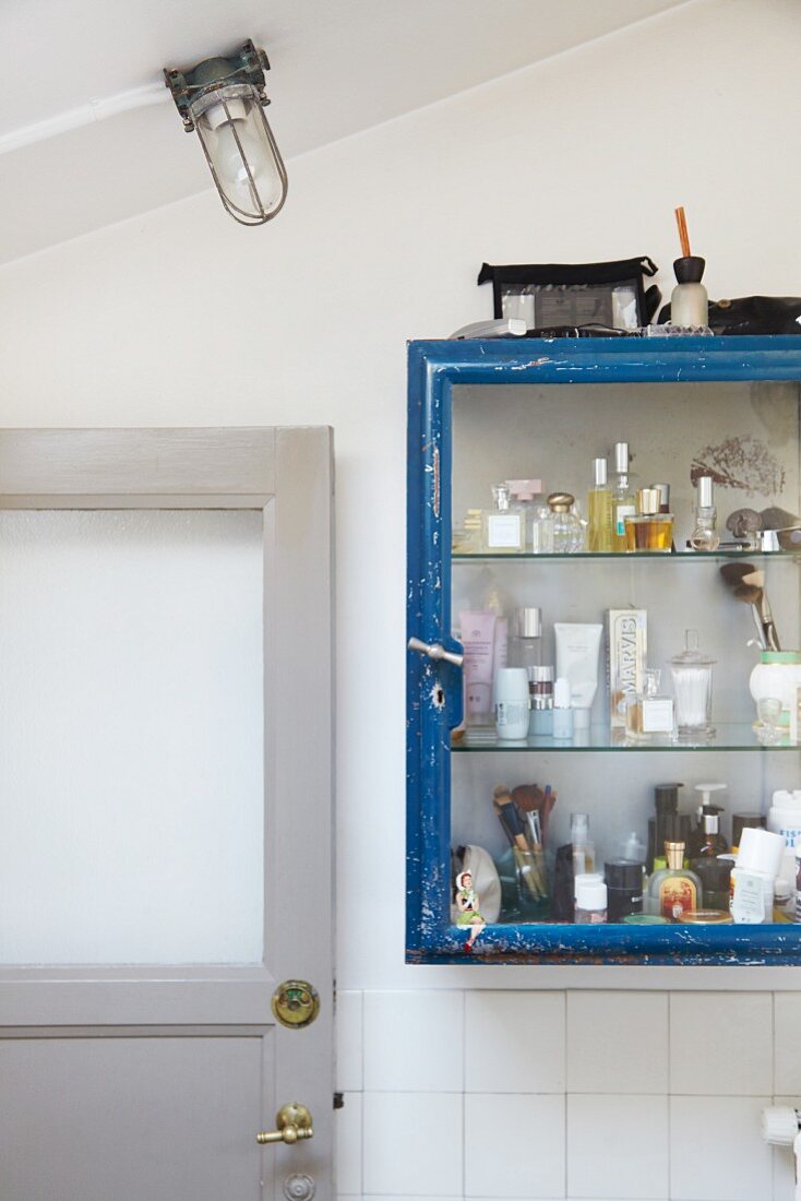 Verschiedene Flacons und Kosmetikartikel in Vintage Vitrinenschränkchen in Badezimmer