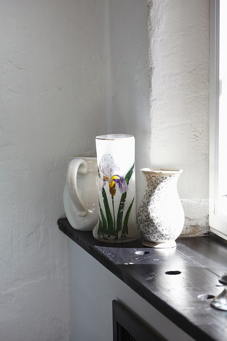 Still-life arrangement of jug and vases on windowsill