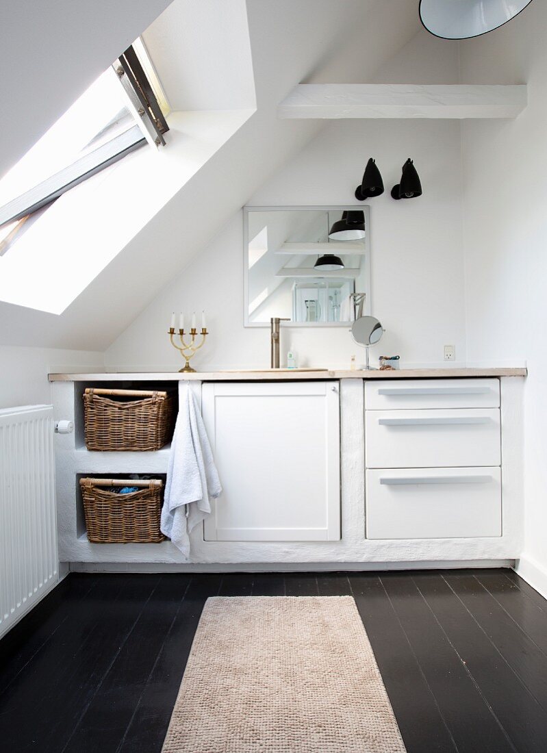 Fitted furnishings in bathroom under sloping ceiling