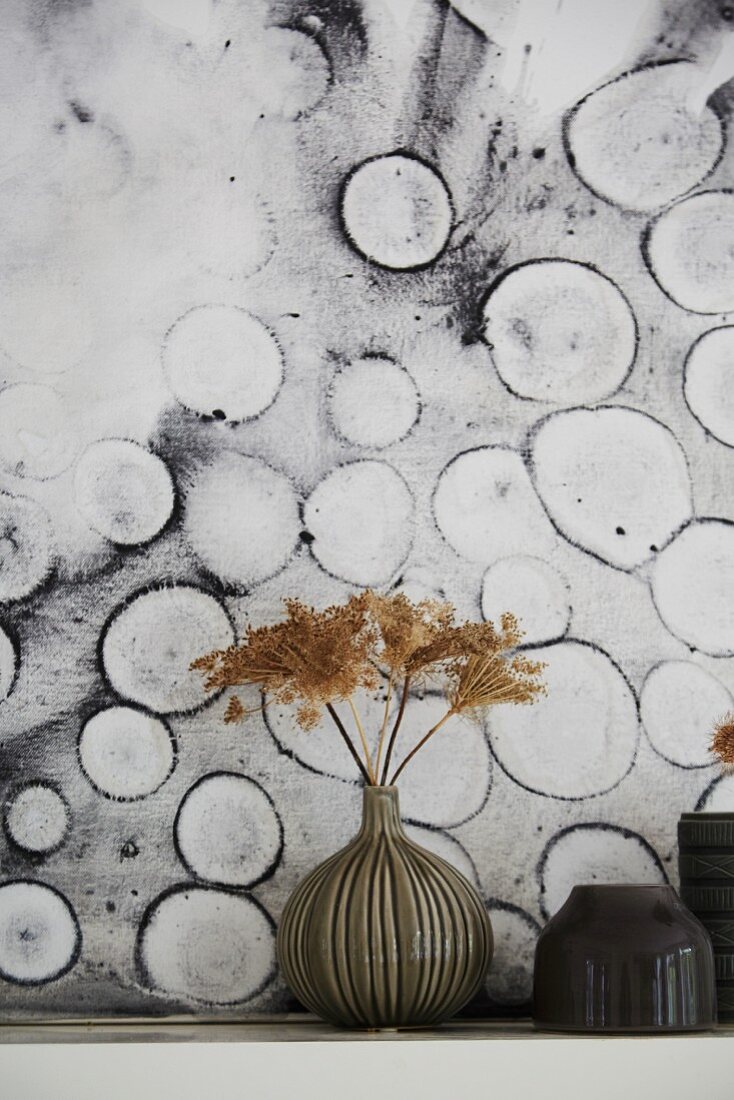 Vase mit getrockneten Blüten vor schwarz-weißer moderner Kunst