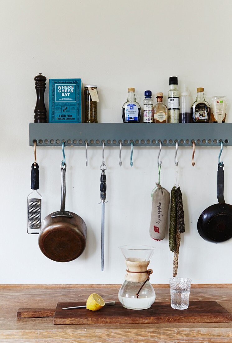 Kitchen utensils on wall-mounted shelf with hooks hung in holes