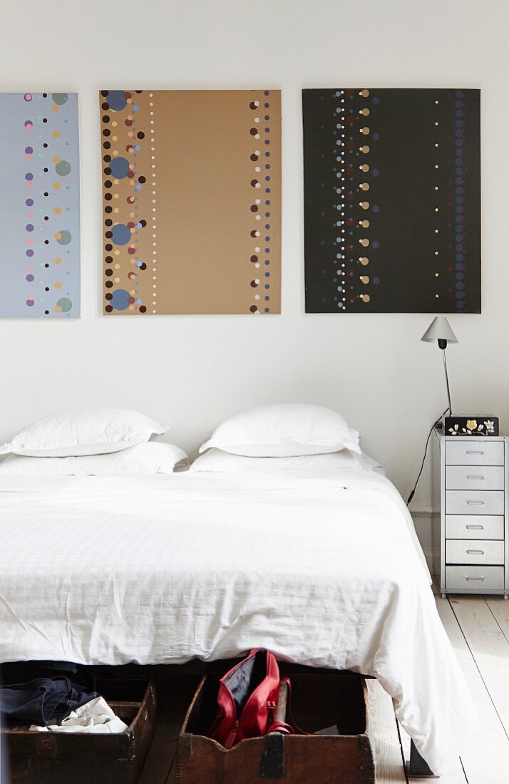 Three artworks with patterns of dots above bed