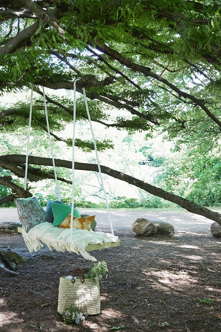 DIY-Schaukelbrett mit Kissen und Fransendecke an Baum aufgehängt