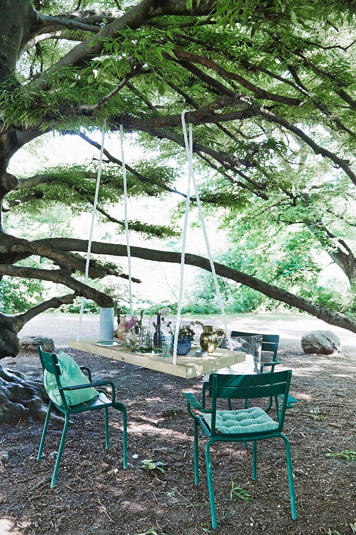 An Ast hängende DIY-Tischplatte und türkisfarbene Gartenstühle