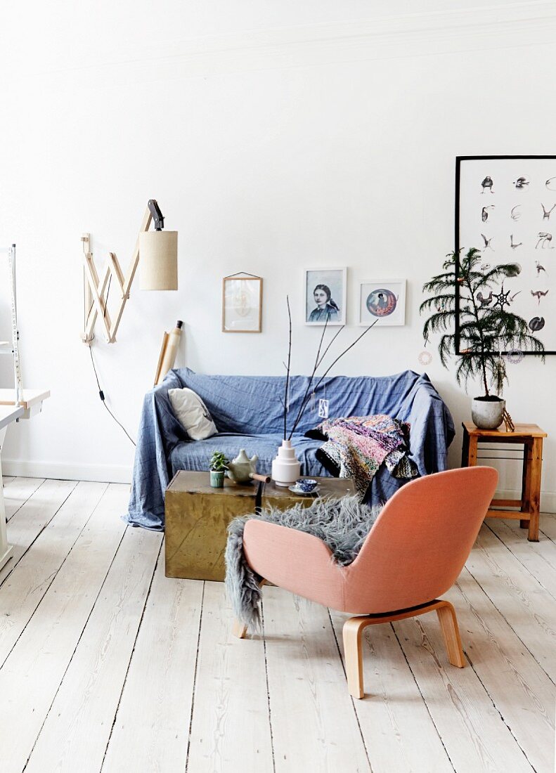 Sofa with blue throw next to potted tree in Scandinavian period apartment
