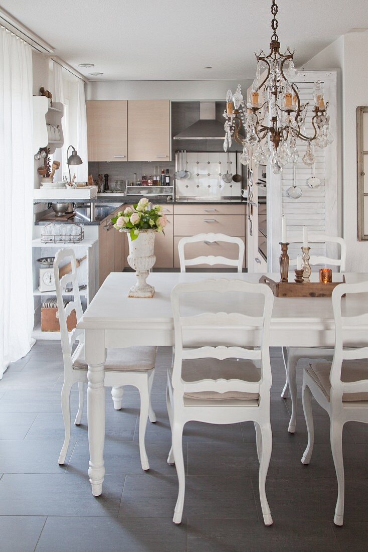 Dining table in front of open-plan, vintage-style kitchen