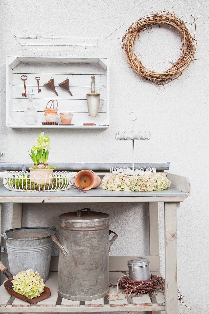Wooden crate used as wall-mounted shelf above ornaments on potting table