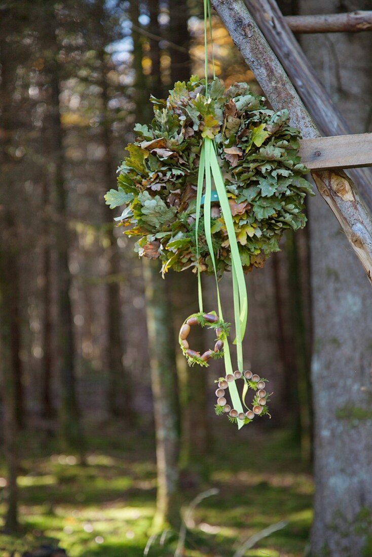 Kranz aus Eichenlaub mit Stoffbändern hängt im Wald