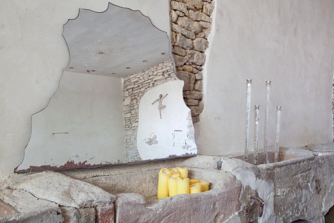 Fragment of mirror leaning against wall, candlesticks and candles in rustic interior