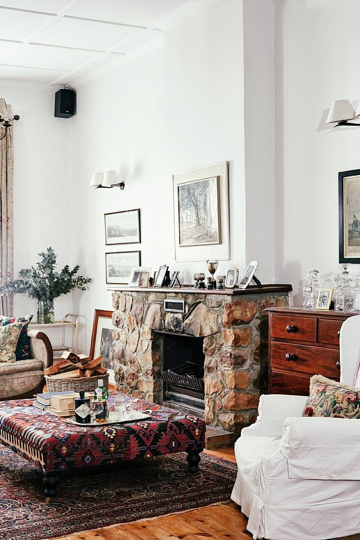 Brick fireplace and patterned ottoman in living room