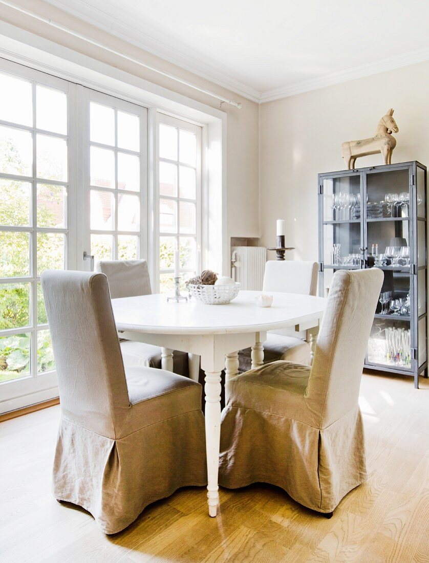 Chairs with beige loose covers around oval dining table