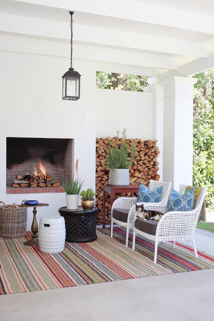 Rug, armchairs and open fireplace on comfortable veranda