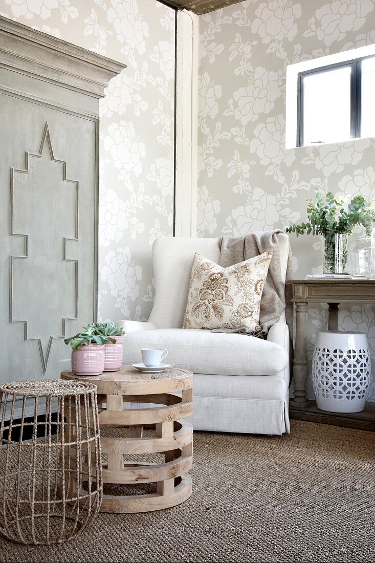 Armchair in corner of cosy living room with floral wallpaper