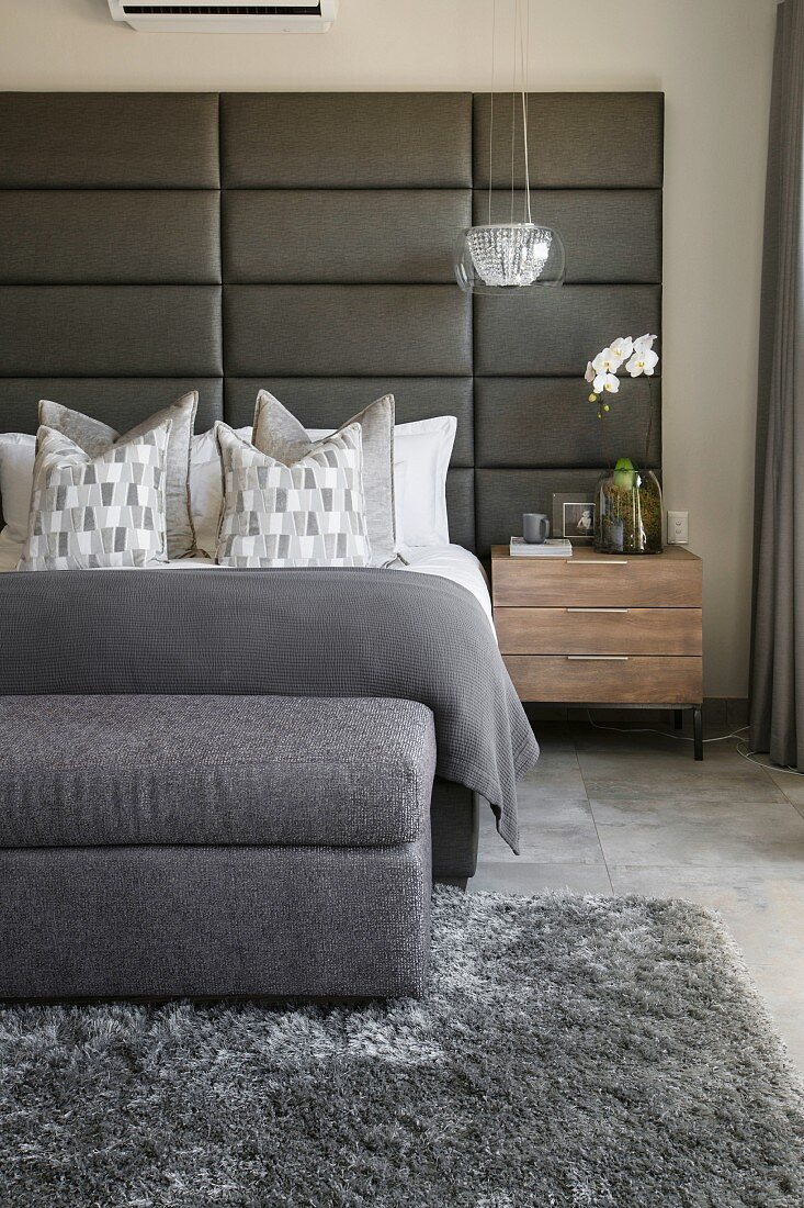 Schlafzimmer in Grautönen mit gepolstertem Betthaupt