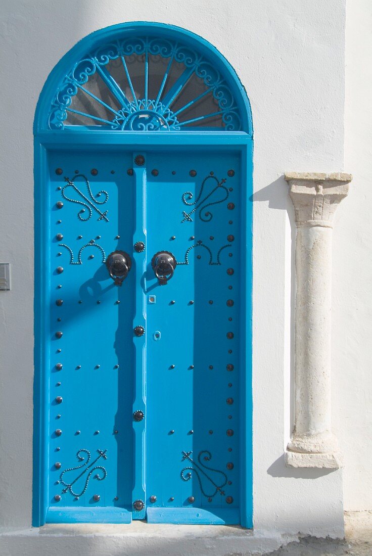 Blaue Tür mit Bogenfenster, eine alte Säule an der Hausecke